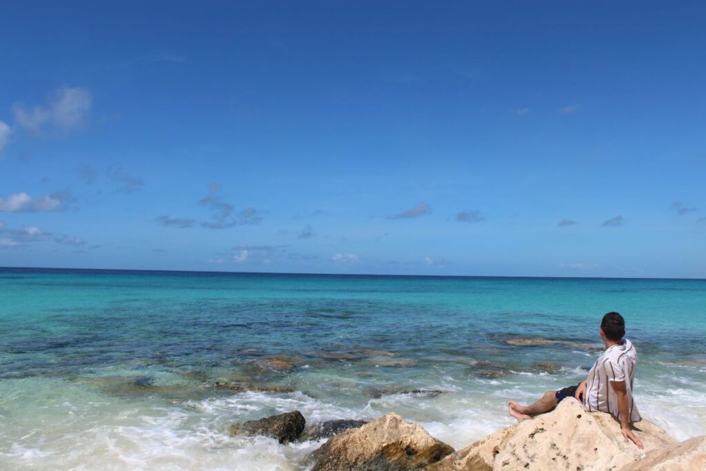 A man sitting on a rock taking in the views at Cies Islands. 
