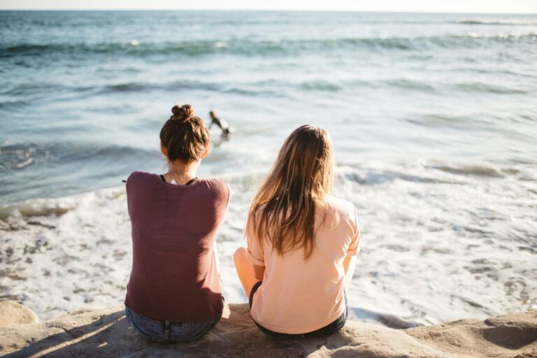 Two women sitting enjoying Vigo beaches.